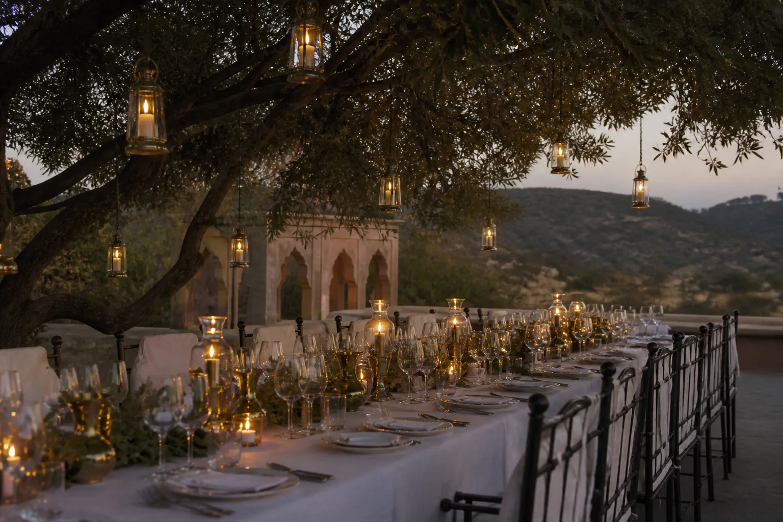 Candlelit outdoor dining under trees at dusk